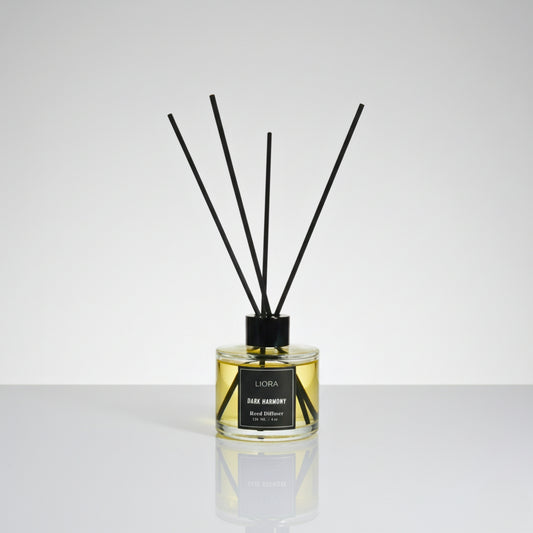 Liora Scentique Dark Harmony reed diffuser with rich yellow oil and black reeds on a marble table with soft lighting, symbolizing luxury sandalwood and oud notes.