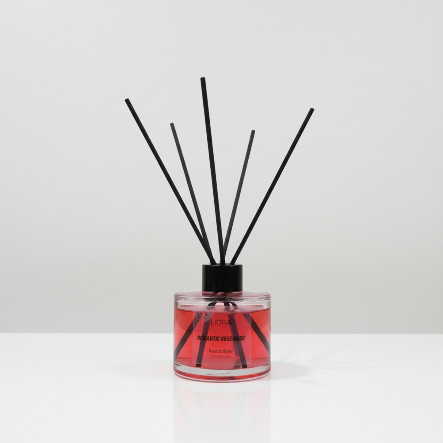 Reed diffuser with black sticks in a clear container on a white background