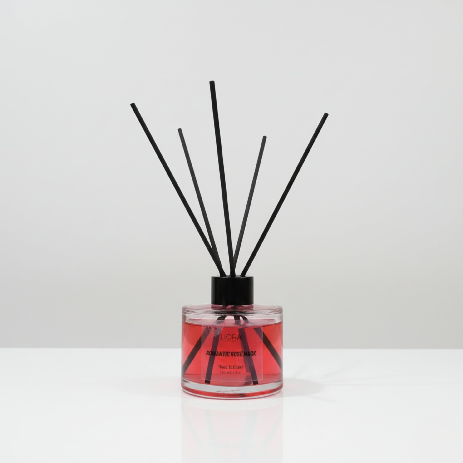Reed diffuser with black sticks in a clear container on a white background