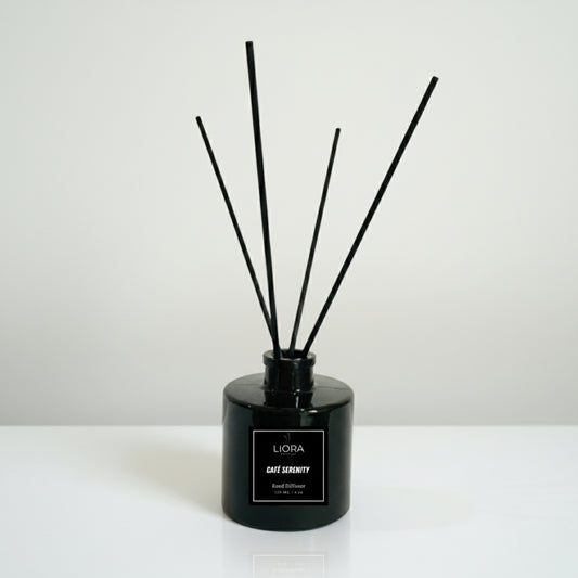 Liora Scentique Café Serenity reed diffuser in a black glass bottle with black reeds, photographed against a clean light grey studio background.