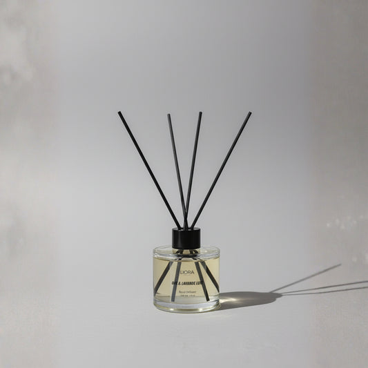Liora Scentique Oak & Lavande Luxe reed diffuser with black reeds, oak chips, and fresh lavender sprig on a wood table