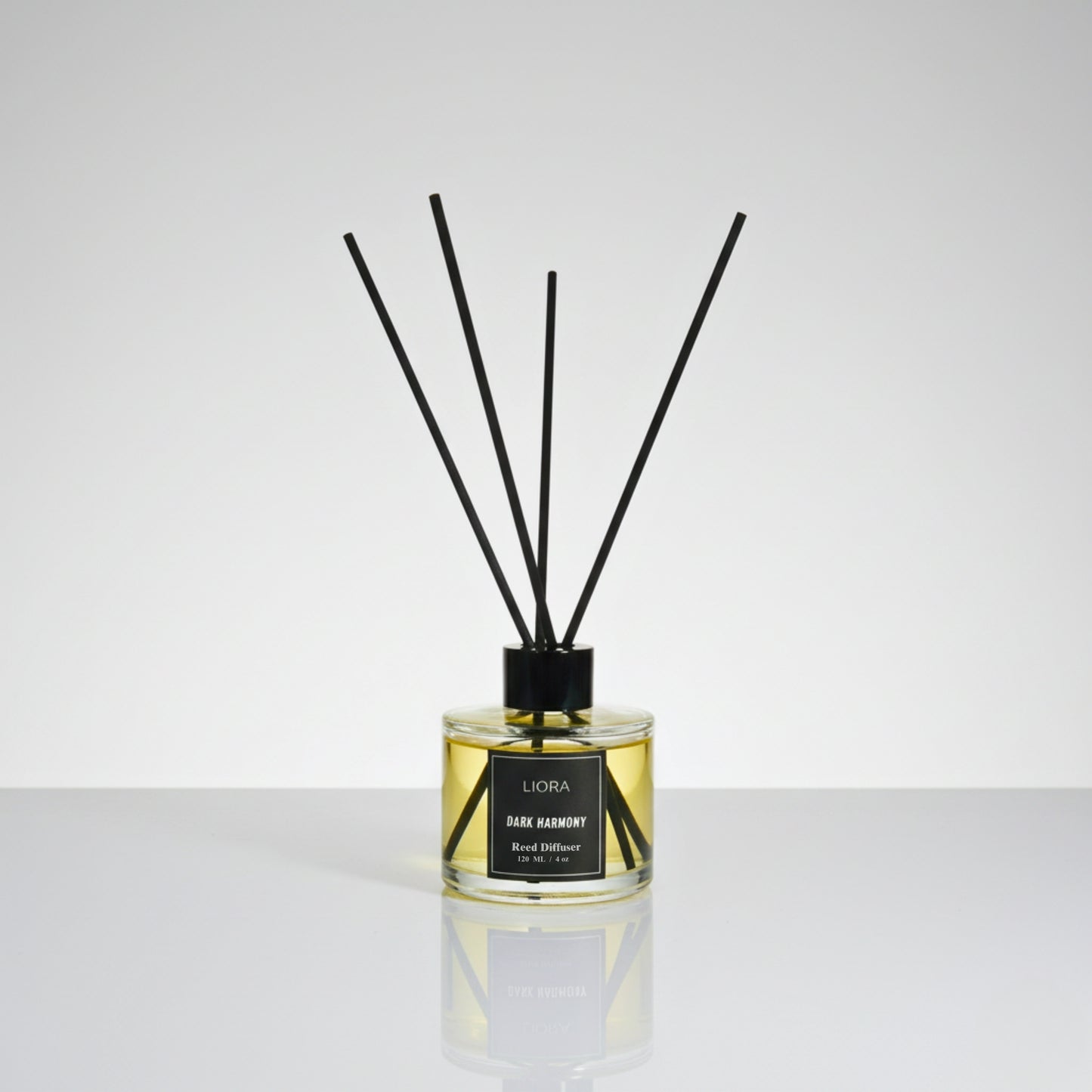 Liora Scentique Dark Harmony reed diffuser with rich yellow oil and black reeds on a marble table with soft lighting, symbolizing luxury sandalwood and oud notes.