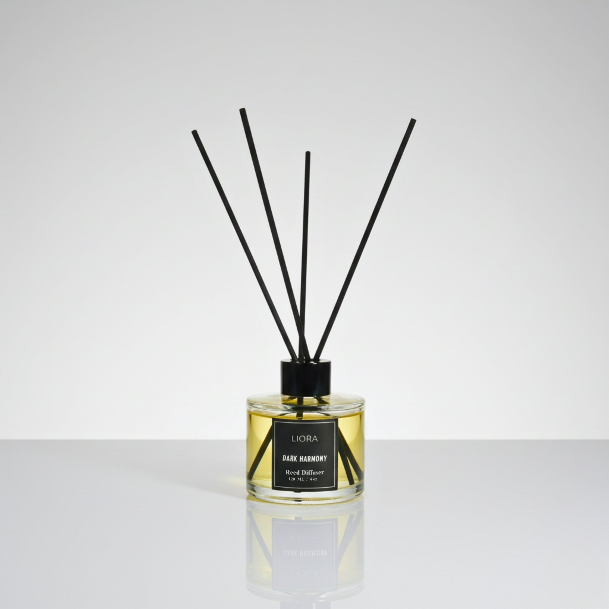 Liora Scentique Dark Harmony reed diffuser with rich yellow oil and black reeds on a marble table with soft lighting, symbolizing luxury sandalwood and oud notes.