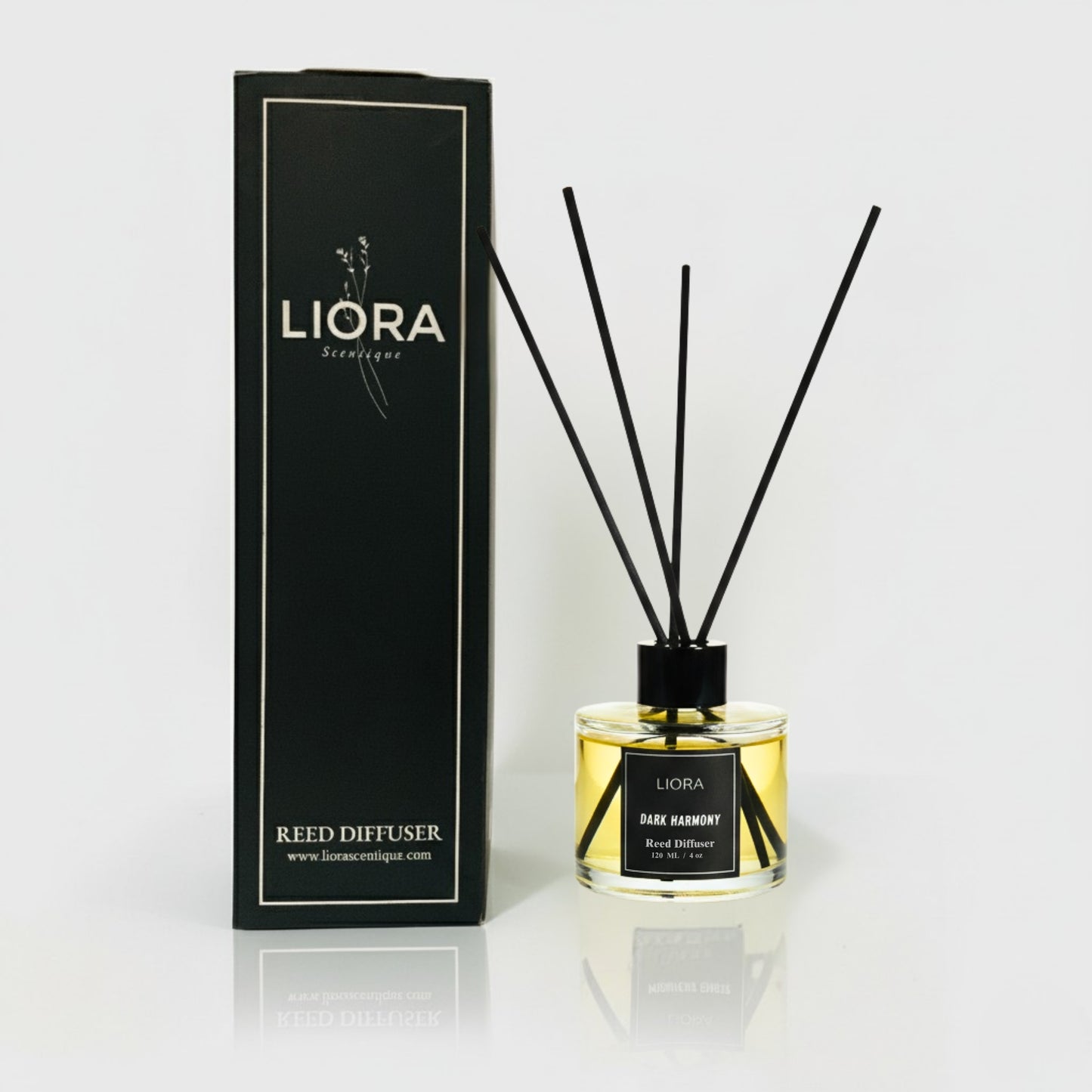 Liora Scentique Dark Harmony reed diffuser with rich yellow oil and black reeds on a marble table with soft lighting, symbolizing luxury sandalwood and oud notes.