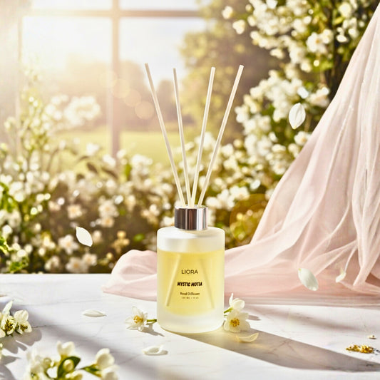 Liora Scentique Mystic Motia reed diffuser on a marble table with white jasmine flowers and soft natural light, showcasing the white reeds and frosted glass bottle.